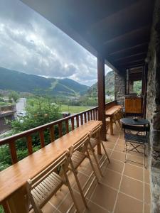 uma varanda com um banco e uma mesa e montanhas em Vall del Riu - Llar dolça llar em Soldeu