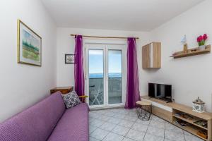 salon z fioletową kanapą i oknem w obiekcie Private accommodation STARA BASKA w mieście Stara Baška