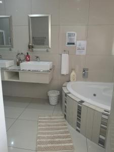 een witte badkamer met een bad en een wastafel bij Mackenzies Accommodation in East London