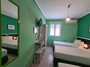 a green room with two beds and a mirror at CH Chelo in Madrid