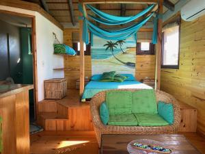 a bedroom with a bed and a chair in a room at caribe in Punta Del Diablo