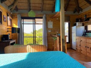 a bedroom with a bed and a kitchen with a refrigerator at caribe in Punta Del Diablo