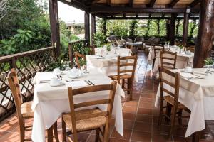 un restaurante con mesas blancas y sillas en un patio en La Jacia Hotel & Resort, en Baja Sardinia