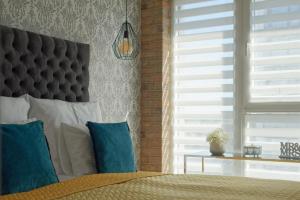 sypialnia z łóżkiem z niebieskimi poduszkami i oknem w obiekcie Malta Apartament IMPERO z Parkingiem w Poznaniu