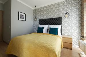 a bedroom with a bed with a yellow bedspread and blue pillows at Malta Apartament Parking by IMPERO in Poznań