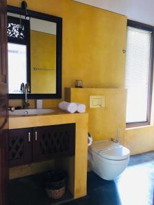 uma casa de banho com um WC, um lavatório e um espelho. em FireMoonGarden by Peacock Villa em Mirissa
