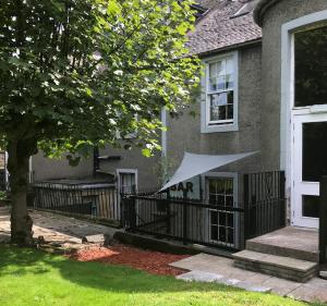 ein Haus mit einem Zaun, auf dem ein weißer Sonnenschirm steht in der Unterkunft Ashtree House Hotel, Glasgow Airport & Paisley in Paisley