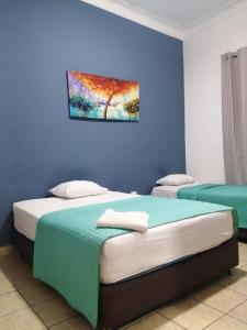 two beds in a room with a painting on the wall at Kayva in Trujillo