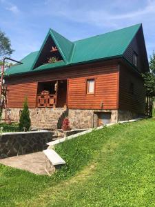 duży drewniany dom z zielonym dachem w obiekcie Садиба Під Чертежиком w mieście Kolochava