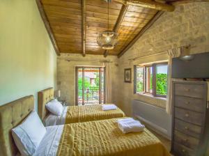 1 dormitorio con 2 camas, TV y ventanas en Christine Countryside House - Fully renovated with all modern comforts, en Rodhopós