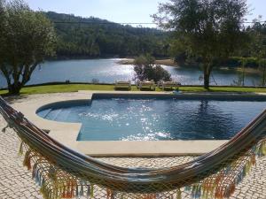 a hammock with a swimming pool and a lake at Casa do Pai Castelo de Bode in Serra