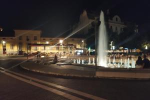 uma fonte no meio de uma rua à noite em Gutenberg utca Apartman Szeged em Szeged