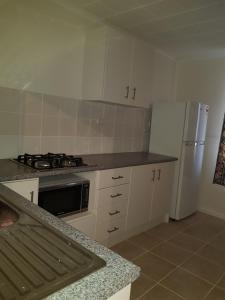 cocina con armarios blancos, fogones y nevera en AGVA OPAL en Coober Pedy