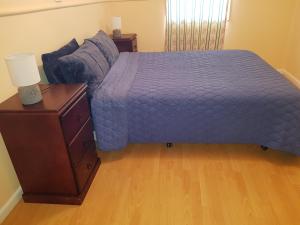 a bed with a purple comforter and a night stand at AGVA OPAL in Coober Pedy