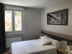 a bedroom with a white bed and two windows at Pensión CHE in O Pedrouzo