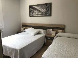 um quarto com duas camas e uma foto na parede em Pensión CHE em O Pedrouzo
