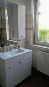 La salle de bains blanche est pourvue d'un lavabo et d'une fenêtre. dans l'établissement Vila v Podkrušnohoří, à Jirkov