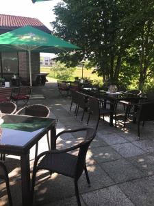 a group of tables and chairs with a green umbrella at Hotel Restaurant Borchard in Lübbecke