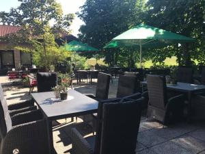 a patio with tables and chairs and a green umbrella at Hotel Restaurant Borchard in Lübbecke