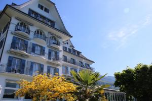 een hoog wit gebouw met balkons en bomen bij Hotel Central Am See - Beau Rivage Collection in Weggis