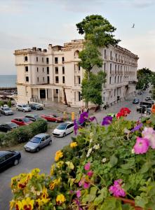 un edificio con coches estacionados en un estacionamiento con flores en La Eluța Cazino en Constanza