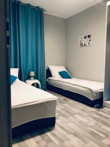 duas camas num quarto com cortinas azuis em Apartament C18 em Jelenia Góra
