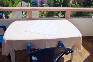 a table with a white table cloth and a chair at Apartmani Vidušin in Novalja