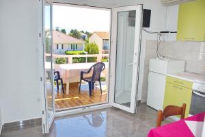 a kitchen with a table and chairs and a balcony at Apartmani Vidušin in Novalja