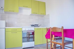 a kitchen with green cabinets and a table and chairs at Apartmani Vidušin in Novalja