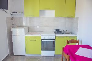 a kitchen with green cabinets and a white stove at Apartmani Vidušin in Novalja