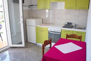 a kitchen with a table with a red table cloth on it at Apartmani Vidušin in Novalja