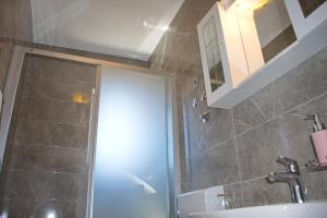 a bathroom with a shower and a sink and a mirror at Apartmani Vidušin in Novalja