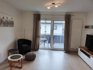 a living room with a tv and a chair and a window at Pension Nickel Ferienwohnung II Waldstraße 18 Alsbach-Hähnlein in Alsbach-Hähnlein