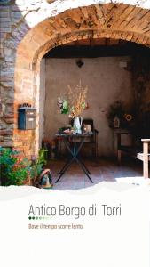 une table avec un vase de fleurs sur elle dans l'établissement Antico Borgo di Torri, à Sovicille