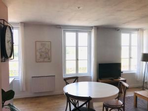 ein Wohnzimmer mit einem Tisch und 2 Fenstern in der Unterkunft Escale face à la Loire in Chaumont-sur-Loire