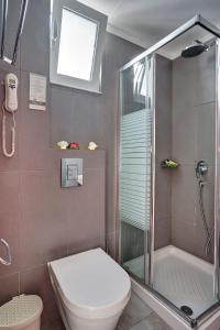 a bathroom with a shower and a toilet and a sink at Castello Di Cavallieri Suites & Spa - Adults Only in Faliraki