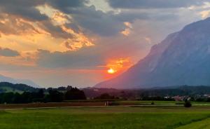 un coucher de soleil dans un champ avec une montagne en arrière-plan dans l'établissement B&B Leonhard 7, à Arnoldstein