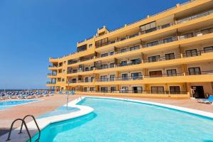a hotel with a swimming pool in front of a building at 330 - Edf Aguamarina - Vacation Rental Home in the coast line of Golf del Sur in San Miguel de Abona
