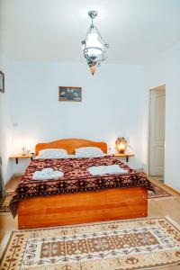 a bedroom with a wooden bed with a chandelier at Casa pe Valea Hartibaciului(Bărcuț) in Bărcuţ