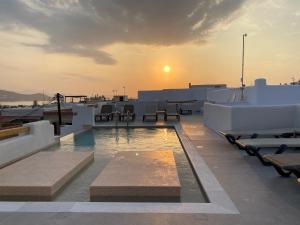 a pool on the roof of a building with the sunset at Ampelos Casart in Naxos Chora