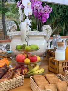 una mesa con fruta y pan y un jarrón de flores en B&B Villa Mamma Rita en Tortora