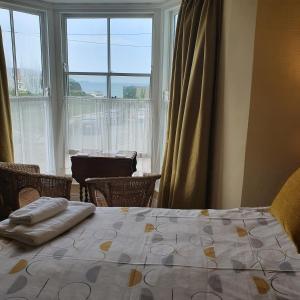 a bedroom with a bed and a large window at Pendyffryn Manor Bed & Breakfast in Little Haven