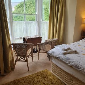 a bedroom with a bed and chairs and a window at Pendyffryn Manor Bed & Breakfast in Little Haven