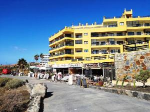 a yellow building next to a street with a building at 330 - Edf Aguamarina - Vacation Rental Home in the coast line of Golf del Sur in San Miguel de Abona