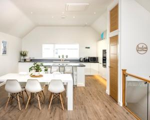 a kitchen and dining room with a white table and chairs at Footsteps to the beach, Seaviews & Beautiful Sunsets in Westward Ho