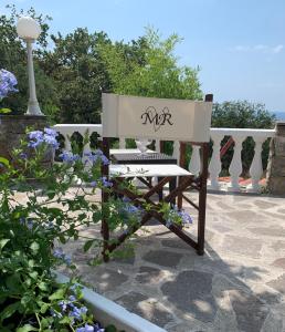 un banco blanco sentado en un patio con flores púrpuras en B&B Villa Mamma Rita en Tortora