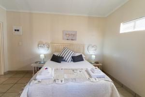 ein Schlafzimmer mit einem Bett mit zwei Tischen und zwei Lampen in der Unterkunft Misty Morn Cottages in Muldersdrift