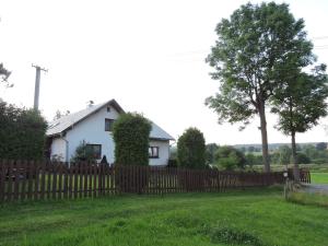 a white house behind a wooden fence at Apartmán Fryšava pod Žákovou horou in Fryšava