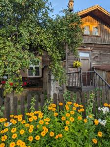 a wooden house with flowers in front of it at Romantisks apartaments ar lapenīti G18 in Līgatne