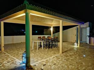 un padiglione con tavolo e sedie su un patio di notte di Keur Lily a Saly Portudal